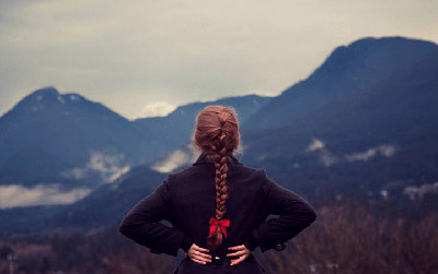 زن با موهای بافته شده در حال نگاه کردن به کوهستان